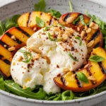 A stunning vegetarian BBQ side dish featuring a classic rocket and peach salad topped with toasted almonds and creamy oozy cheese.