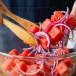 Making this Watermelon Mint Feta Salad is incredibly straightforward. It is practically foolproof! 1.Prep the Watermelon: Cut your cold, seedless watermelon into bite-sized, one-inch cubes. Place the cubes into a large serving bowl. 2.Slice the Veggies and Herbs: Finely slice your red onion. Chiffonade (thinly slice) your fresh mint leaves. Add them to the bowl. 3.Crumble the Feta: Take your block of feta cheese and roughly crumble it over the top of the watermelon mixture. 4.Add the Citrus: Cut a fresh lime in half and squeeze the juice directly over the salad. 5.Drizzle and Serve: Right before you are ready to eat, drizzle the balsamic vinegar over the top. Toss very gently and serve immediately.