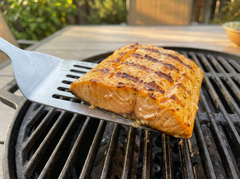 Flipping a tender mahi mahi fillet with a metal spatula showing dark caramelized grill marks on the grates.